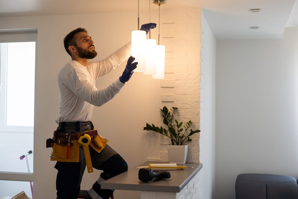 Technicien installant un luminaire suspendu dans des locaux professionnels
